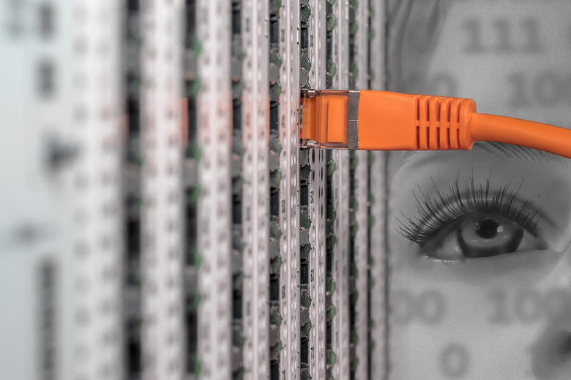 ein einzelnes Netzwerkkabel in einem Patchfeld, darüber ein Gesicht projiziert